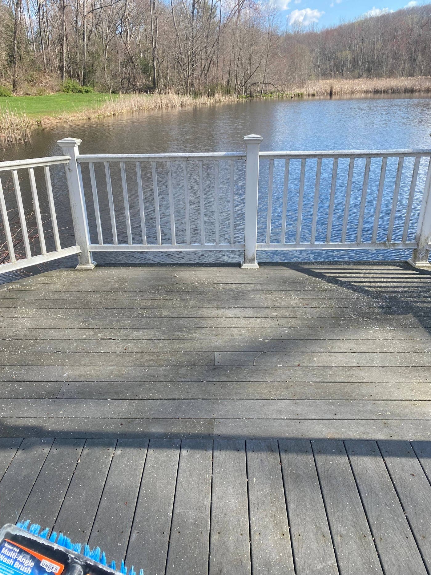 Dirty weathered composite deck overlooking a pond before cleaning